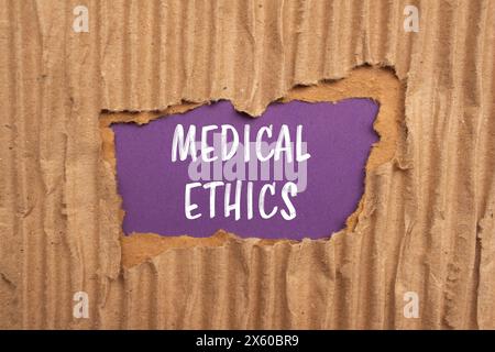 Mots d'éthique médicale écrits sur papier carton déchiré avec fond violet. Symbole conceptuel de l'éthique médicale. Copier l'espace. Banque D'Images