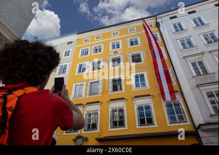 Salzbourg, Autriche, 15 août 2022. Un garçon mignon photographie la maison de mozart avec son téléphone portable comme souvenir de la fête. Concept d'utilisation de la technologie Banque D'Images