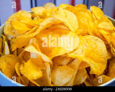 Heure de la collation. Croustilles éclatantes dans un bol bleu, idéales pour les repas décontractés. Banque D'Images