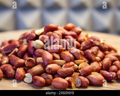 Cacahuètes sur bois. Cacahuètes décortiquées dispersées sur une surface en bois, idéales pour les thèmes de l'alimentation et de la nutrition. Banque D'Images