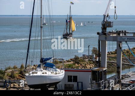 Bootssport am Atlantik. Ein antikes Segelboot, ein Zweimaster, Hat soeben den Jachthafen von Pornic verlassen. IM Vordergrund sind Bestandteile des Hafens mit Kran und einer aufgebockten Segeljacht zu sehen. IM Hintergrund üben Kinder dans ihren Jollen. Pornic Loire-Atlantique Frankreich *** bateau sur l'Atlantique un voilier antique, un deux-maître, vient de quitter la marina de Pornic au premier plan, vous pouvez voir des parties du port avec une grue et un yacht à voile à cric en arrière-plan, enfants pratiquant dans leurs canots Pornic Loire Atlantique France Banque D'Images