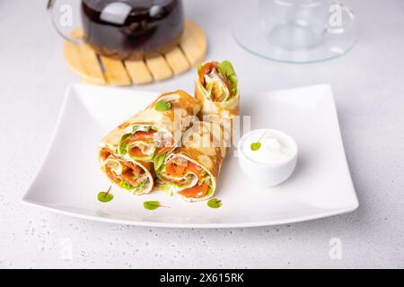 Crêpes au saumon (truite), crème sure, verdstuff et thé. Fin, pas doux blinchiki farci de poisson rouge. Plat traditionnel russe et ukrainien. Banque D'Images