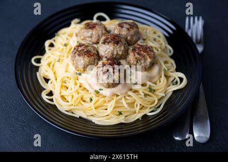 noisettes suédoises (fricadelles) avec spaghetti et sauce crémeuse à la crème de Brune Sos. Boulettes de viande traditionnelles avec garniture. Mise au point sélective, gros plan. Banque D'Images