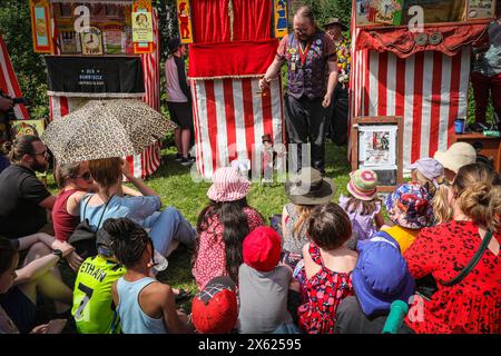 Londres, Royaume-Uni. 12 mai 2024. Enfants et adultes regardent un spectacle de l'un des membres de la Punch & Judy Fellowship. L'après-midi, un certain nombre de spectacles traditionnels et modernes de Punch et Judy divertissent la foule. Les marionnettistes de tout le pays se rassemblent pour le festival annuel de mai Fayre and Puppet. Il se déroule dans les jardins de l'église St Paul (également appelée église de l'acteur), Covent Garden et comprend un service religieux, une procession, des spectacles de Punch et Judy, des ateliers, des stands et des divertissements en famille. Crédit : Imageplotter/Alamy Live News Banque D'Images