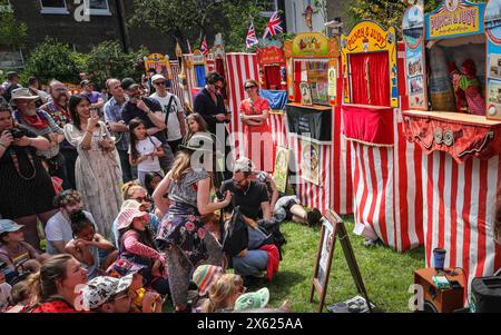 Londres, Royaume-Uni. 12 mai 2024. Enfants et adultes regardent un spectacle de l'un des membres de la Punch & Judy Fellowship. L'après-midi, un certain nombre de spectacles traditionnels et modernes de Punch et Judy divertissent la foule. Les marionnettistes de tout le pays se rassemblent pour le festival annuel de mai Fayre and Puppet. Il se déroule dans les jardins de l'église St Paul (également appelée église de l'acteur), Covent Garden et comprend un service religieux, une procession, des spectacles de Punch et Judy, des ateliers, des stands et des divertissements en famille. Crédit : Imageplotter/Alamy Live News Banque D'Images