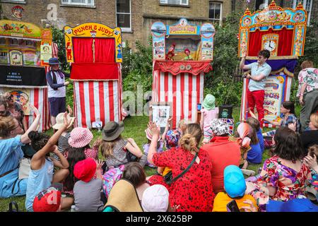 Londres, Royaume-Uni. 12 mai 2024. Enfants et adultes regardent un spectacle de l'un des membres de la Punch & Judy Fellowship. L'après-midi, un certain nombre de spectacles traditionnels et modernes de Punch et Judy divertissent la foule. Les marionnettistes de tout le pays se rassemblent pour le festival annuel de mai Fayre and Puppet. Il se déroule dans les jardins de l'église St Paul (également appelée église de l'acteur), Covent Garden et comprend un service religieux, une procession, des spectacles de Punch et Judy, des ateliers, des stands et des divertissements en famille. Crédit : Imageplotter/Alamy Live News Banque D'Images