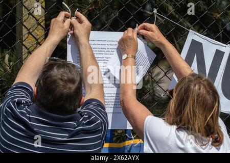 Lakenheath, Royaume-Uni. 11 mai 2024. Les résidents locaux fixent un avis sur la clôture périphérique de la RAF Lakenheath déclarant qu'elle est une zone exempte d'armes nucléaires lors d'une manifestation organisée par la campagne pour le désarmement nucléaire (CND) devant la base. Les manifestants ont appelé le gouvernement britannique à refuser la livraison de bombes nucléaires américaines B61-12 à la base. Il faisait partie d'une journée nationale d'action de la CND. Crédit : Mark Kerrison/Alamy Live News Banque D'Images