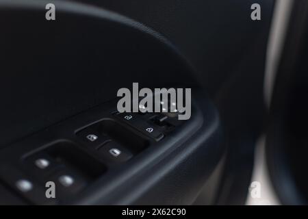 Bloc de boutons de commande des vitres électriques, etc. Dans la porte avant du conducteur d'une voiture de tourisme gros plan sur fond flou Banque D'Images