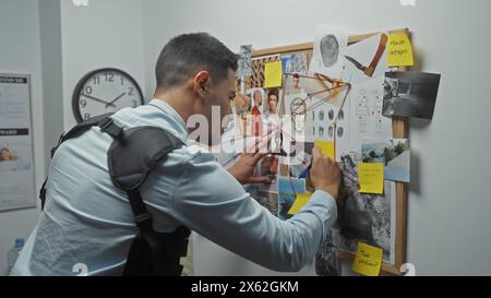 Jeune homme hispanique analysant les preuves criminelles sur un tableau du département de police. Banque D'Images