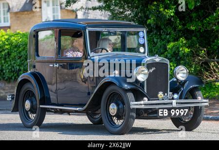 Stoke Goldington, Royaume-Uni - 12 mai 2024:1933 Austin voiture vintage conduisant sur une route britannique Banque D'Images