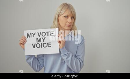 Une femme d'âge moyen aux cheveux blonds, debout sur un fond blanc, tient un panneau sur le droit de vote. Banque D'Images