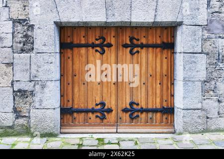 Une porte médiévale rustique en bois avec des charnières en fer noir sertie dans un ancien mur de pierre. Banque D'Images