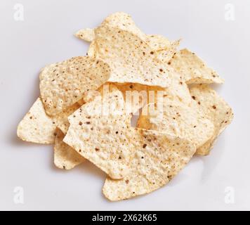 Un tas de chips tortilla croustillantes dispersées sur un fond blanc Uni, parfait pour les collations ou les menus de fête. Banque D'Images