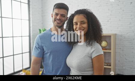 Un couple souriant se tient ensemble dans un salon lumineux, exsudant l'amour et la compagnie dans un cadre confortable à la maison. Banque D'Images