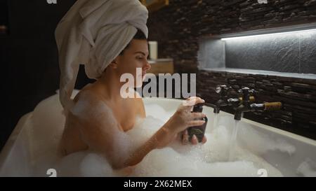Femme détendue profitant d'un bain moussant de luxe dans une salle de bain moderne à la maison Banque D'Images