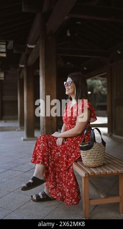 Été lumineux au temple meiji, belle femme hispanique en lunettes, rayonnant de positivité tout en étant assise seule sur le banc du parc, souriant et profitant de tokyo Banque D'Images