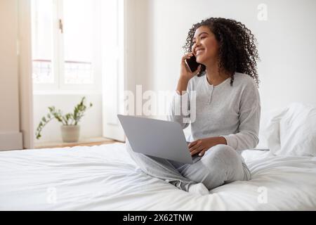 Sourire jeune femme travaillant à domicile sur son ordinateur portable Banque D'Images