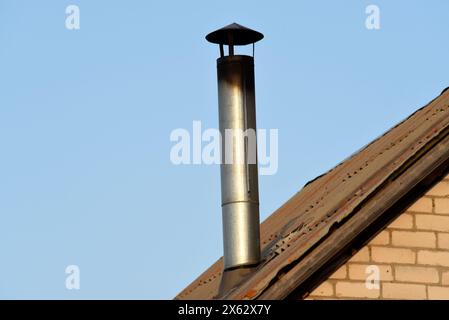 Une cheminée sur un fond de ciel bleu. Une cheminée en fer brillant. Banque D'Images