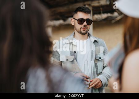 Jeune homme appréciant la conversation avec des amis lors d'une sortie de groupe Banque D'Images