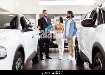 Vendeur professionnel présentant de nouveaux modèles de voiture à coupler au Showroom Banque D'Images