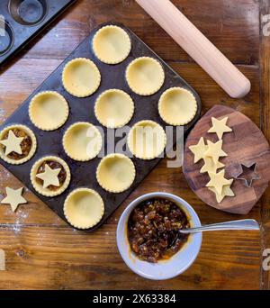 Vue en plan d'un moule à petits pains en métal recouvert de pâtisseries, prêt pour des tartes hachées recouvertes d'étoiles. Banque D'Images