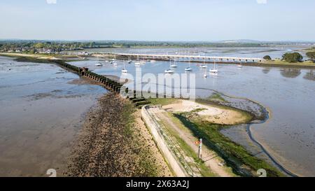 Vestiges d'un vieux pont ferroviaire entre Langstone (haut de la photo) et Hayling Island dans le Hampshire, Royaume-Uni, avec un pont routier derrière Banque D'Images