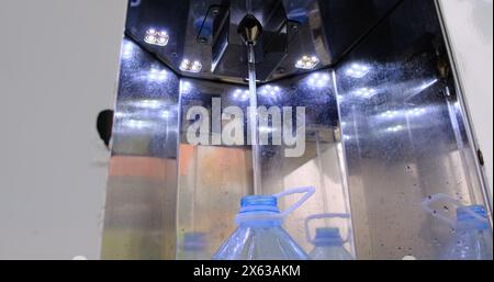 Gros plan de verser de l'eau avec une bouteille d'eau en plastique de 5 litres à la station de filtration d'eau locale avec machine de filtration d'eau du système automatique Banque D'Images