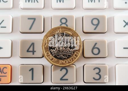 Pièce britannique d'une livre placée sur le dessus des boutons de la calculatrice. Concept pour les affaires, la planification et la finance Banque D'Images
