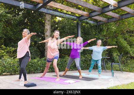 Diverses amies seniors pratiquant le yoga à l'extérieur, appréciant le fond vert Banque D'Images