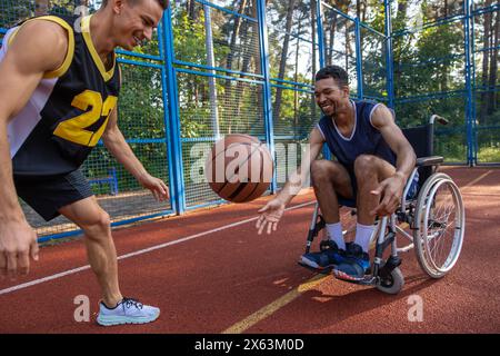 Joueur de basketball en fauteuil roulant homme jouant une compétition de match avec un ami sur le court Banque D'Images