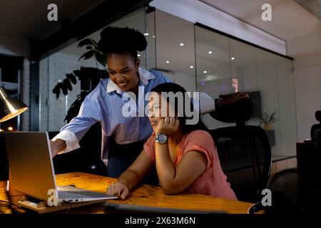 Diverses collègues femmes d'affaires discutant du travail la nuit, travaillant tard Banque D'Images