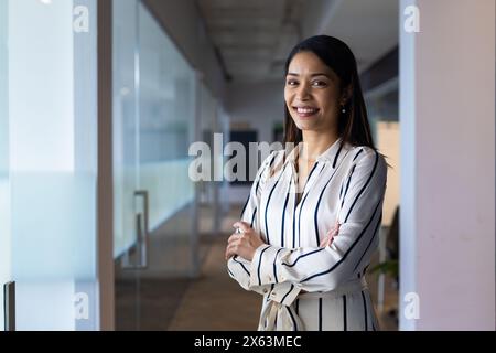 Manager féminin biracial d'âge moyen debout avec les bras croisés au bureau, espace de copie Banque D'Images