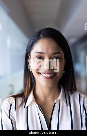 Une professionnelle biraciale d'âge moyen souriant à la caméra au bureau Banque D'Images