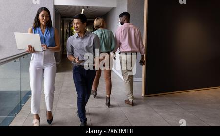 Au bureau, équipe diversifiée marchant, discutant du travail Banque D'Images
