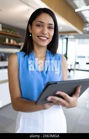 Responsable biracial d'âge moyen tenant une tablette au bureau Banque D'Images