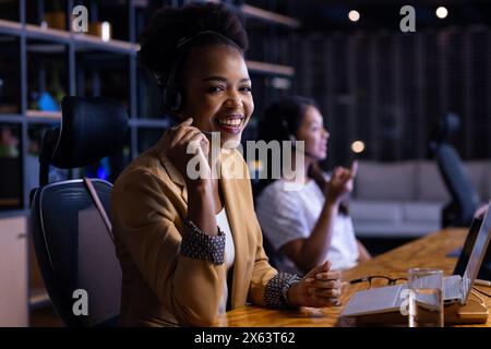 Au bureau, diverses collègues féminines d'affaires souriant, se concentrant, travaillant tard Banque D'Images