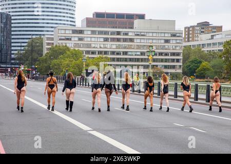 Vue arrière des filles en léotards noirs marchent le long du pont Westminster Londres vers l'hôpital universitaire St Thomas's NHS, les femmes protestent / pouvoir, Londres Banque D'Images