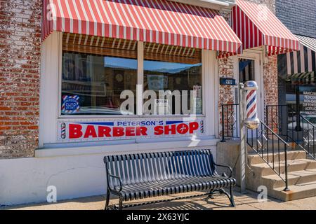 Princeton, il, États-Unis-28 février 2024 : entrée principale à l'ancienne, petite ville de barbier avec auvent rayé rouge vif et poteau de barbier classique. Banque D'Images