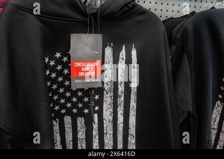 Gros plan du sweat-shirt noir caché à vendre dans un magasin de détail avec drapeau américain stylisé noir et blanc sur le devant du sweat-shirt. Banque D'Images