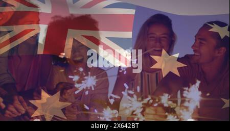 Image composite du drapeau australien au-dessus d'un groupe d'amis divers célébrant avec des étincelles sur la plage Banque D'Images