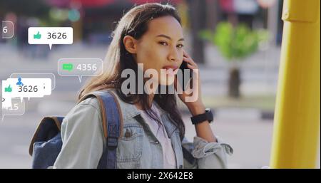 Image de plusieurs barres de notification sur une femme asiatique souriante parlant sur smartphone Banque D'Images