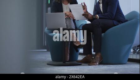 Image d'un chef d'équipe caucasien et d'un collègue afro-américain examinant des documents Banque D'Images