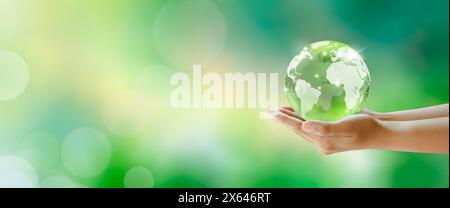 Boule de verre de cristal de globe dans les mains. Vert fond ensoleillé avec bokeh. Santé mentale mondiale et journée mondiale de la terre. Sauver l'environnement et l'écologie mondiale Banque D'Images