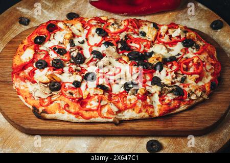 Pizza artisanale avec olives et poivrons sur planche à découper en bois Banque D'Images