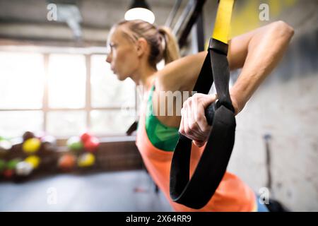 Belle femme de sport faisant un entraînement de suspension, exercice de résistance totale. Entraînement de routine pour la santé physique et mentale de la femme. Banque D'Images