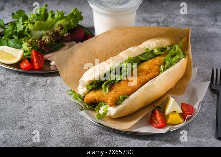 Sandwich au poisson frit avec des légumes verts sur la table en pierre. Nom turc Balik Ekmek Banque D'Images