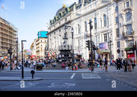 Visiteurs et touristes à Piccadilly Circus London West End, assis à côté de la statue d'Eros en face du magasin Lillywhites, Londres, Angleterre, 2023 Banque D'Images