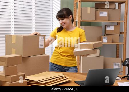 Emballage de colis. Employé de bureau de poste avec des colis à la table en bois à l'intérieur Banque D'Images