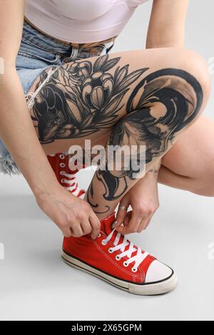 Femme avec des tatouages cool sur fond clair, gros plan Banque D'Images