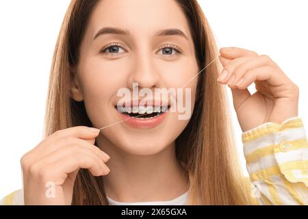 Femme souriante avec des bagues nettoyant les dents à l'aide de fil dentaire sur fond blanc, gros plan Banque D'Images